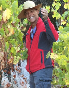 Bill O'Brien picking grapes photo wearing red jacket and straw hat with big smile