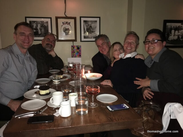 Group of friends sitting at table with drinks and food