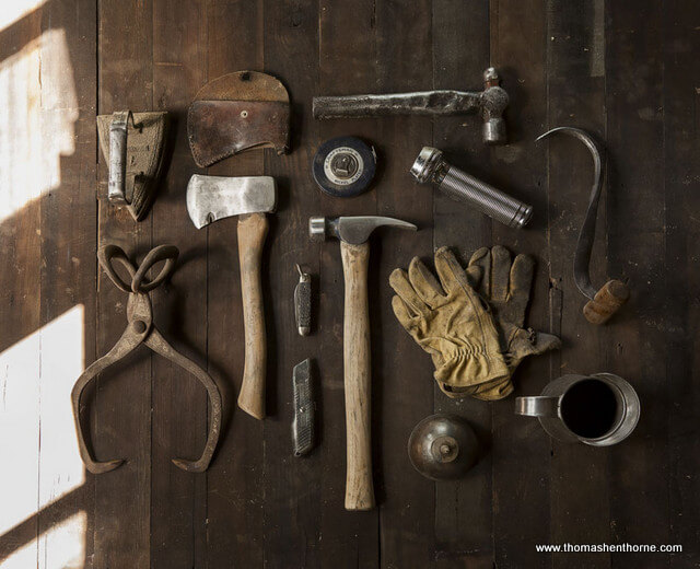 Still life image of some rustic tools on worn wood background for marin county permits article - photo of hammer gloves axe and other tools