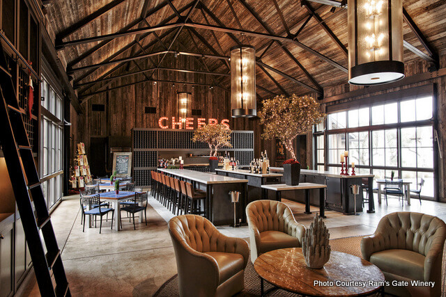 photo of main tasting room at Ram's Gate Winery with table and chairs in foreground beamed ceilings and large marble bar