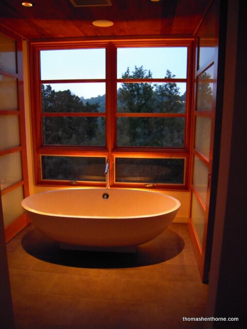 bathroom remodel photo of tub at sunset with sky in background and lights shining ontub