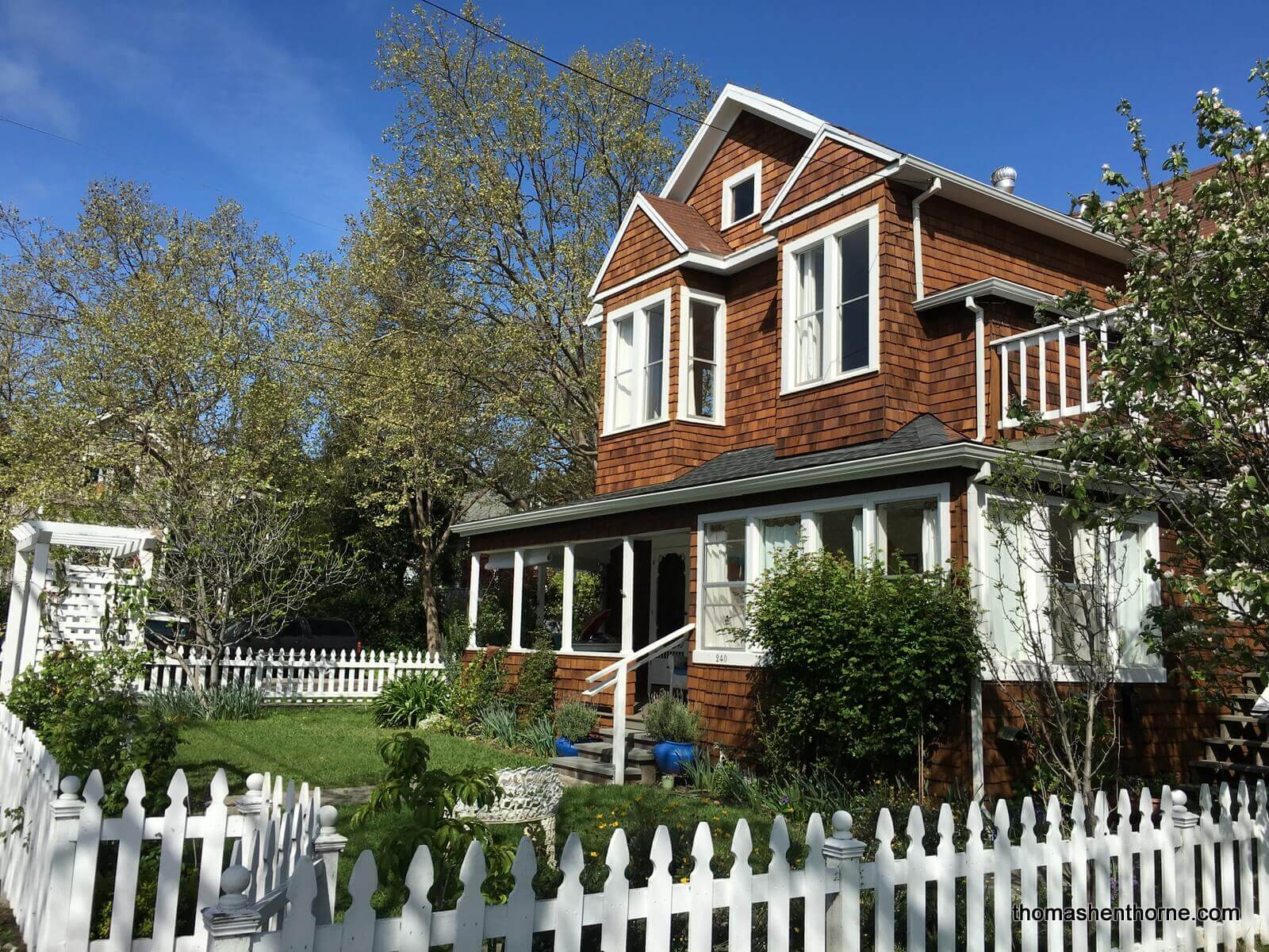 photo of home with shingles white trim and white picket fence