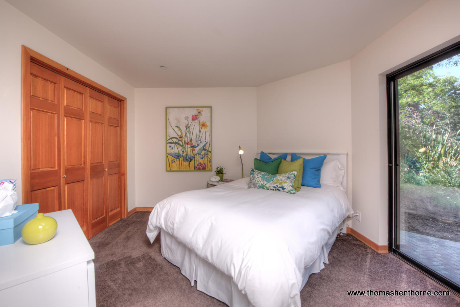 Guest room with white comforter on bed and slider to right