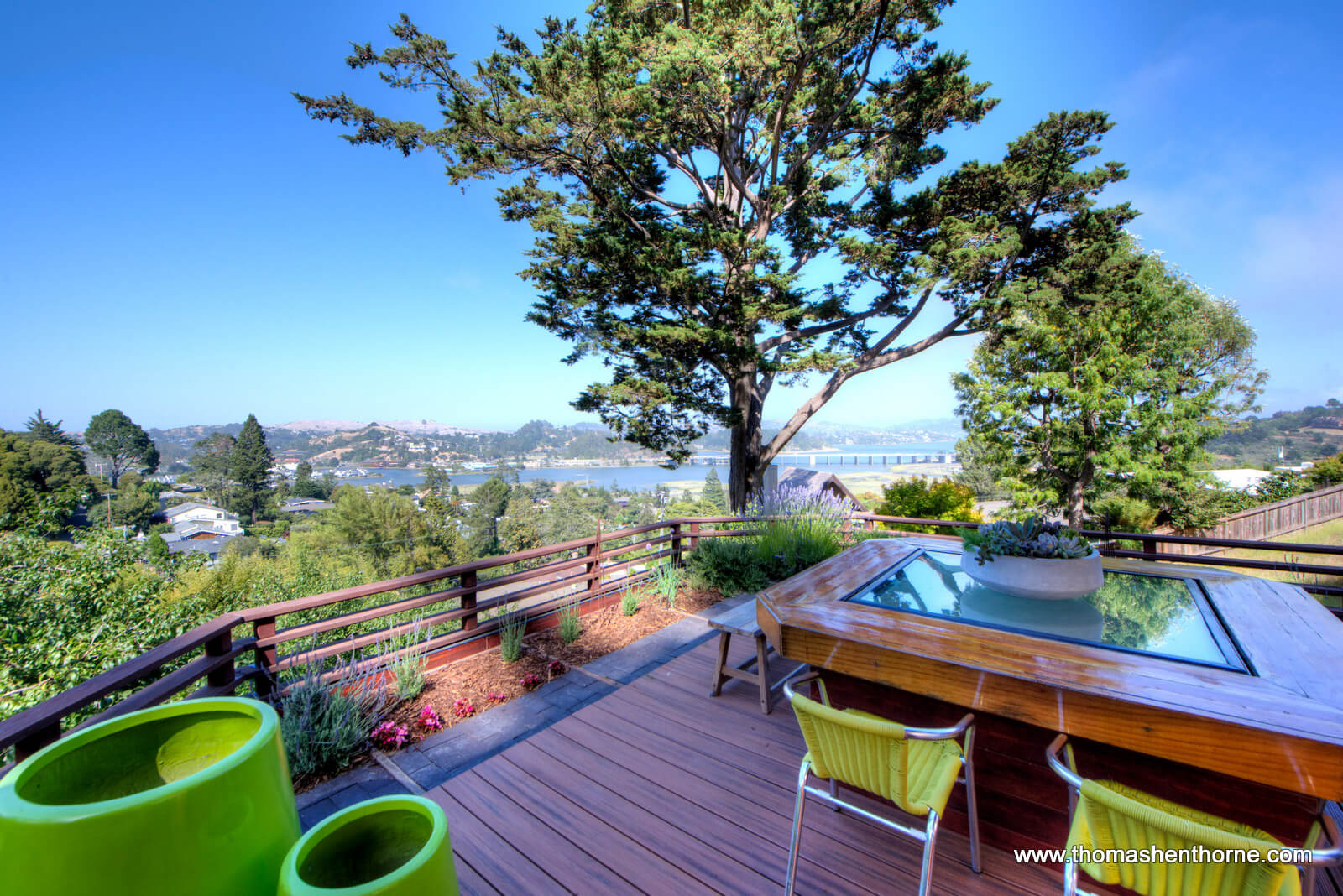 Deck with chartreuse pots and chairs and bay in distance