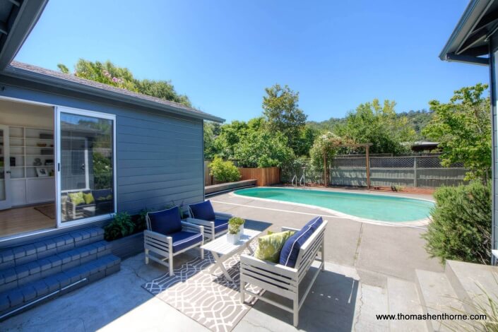 Back patio with pool and family room with open sliding doors