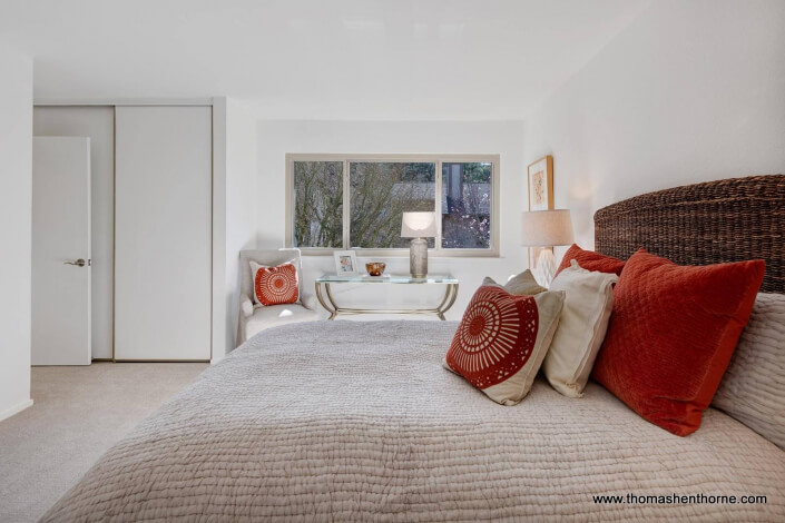 Bed with rust colored pillows and window