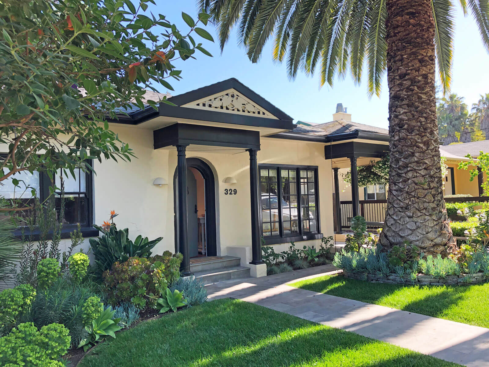 Front exterior of bungalow in San Anselmo, California with green lawn and large canary island palm