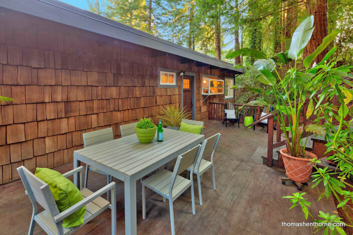 Outdoor dining table on wood deck with shingled home