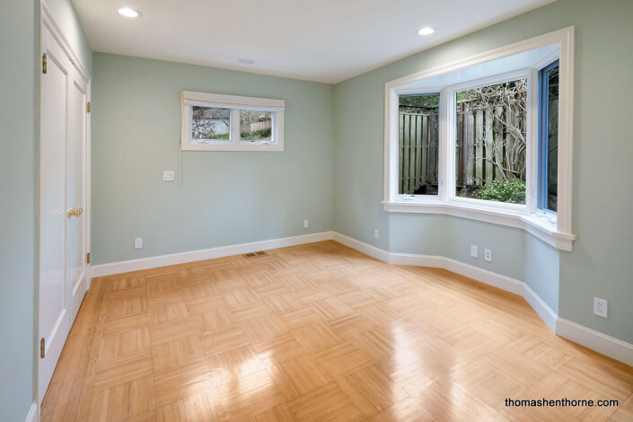 Room with green walls and white trim and parquet floors