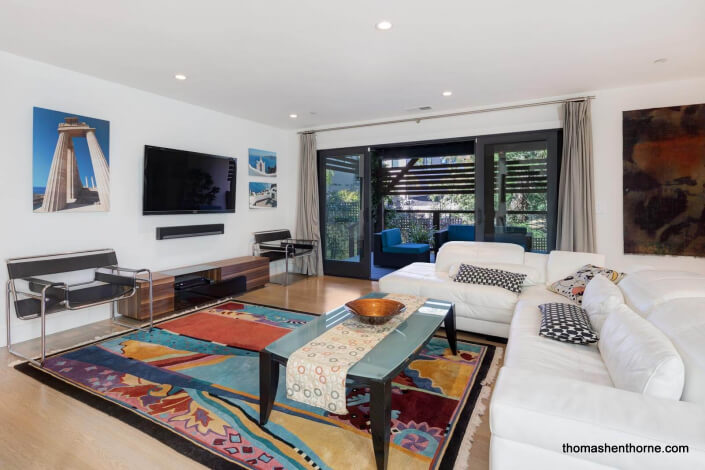 Living room with TV on wall and glass sliding doors to deck