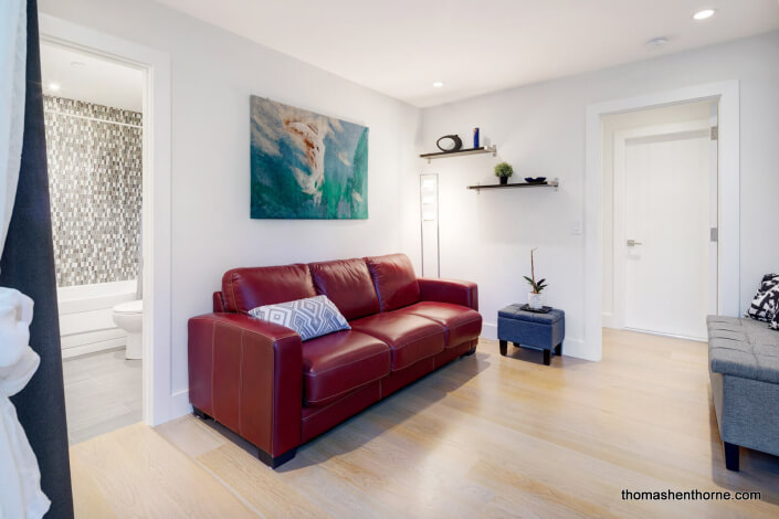 Bedroom with red leather sofa and wide plank floors