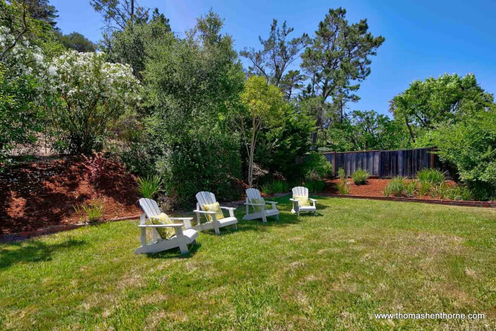 Four Adirondack chairs on green grass