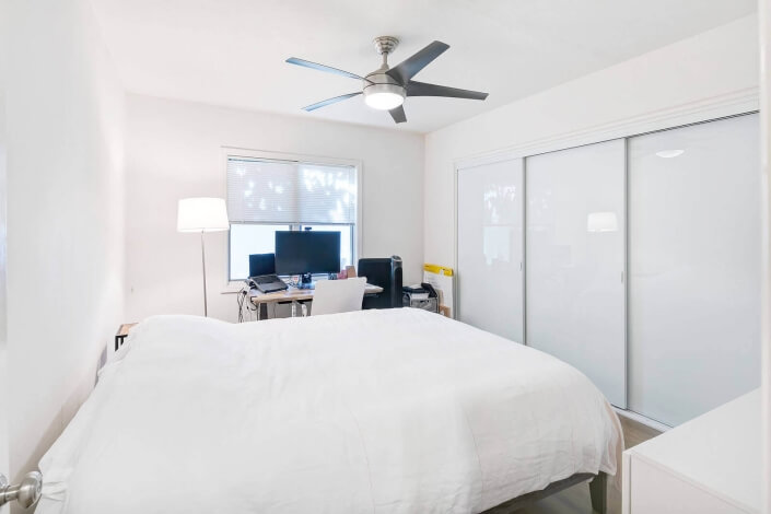 bedroom with ceiling fan and white closet doors