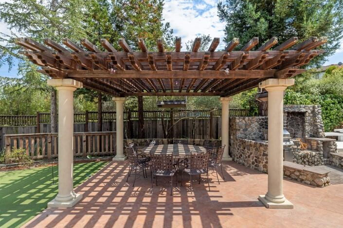 outdoor kitchen and dining table under trellis