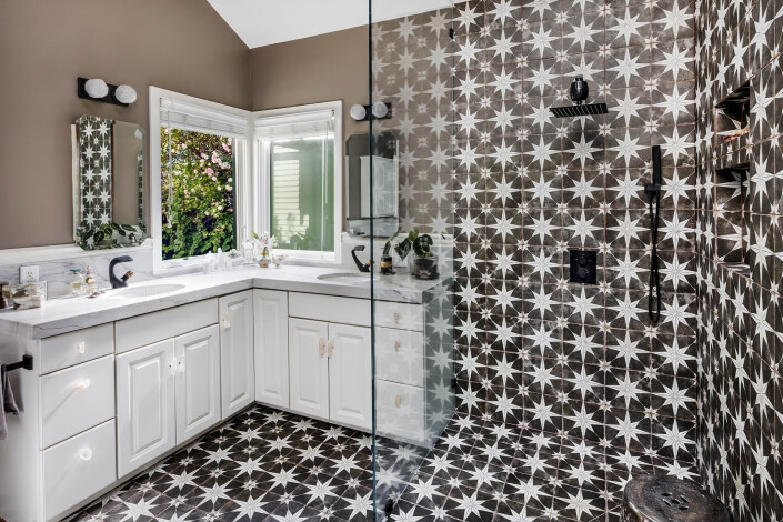 Primary bathroom with dual sinks and walk in shower with geometric tile