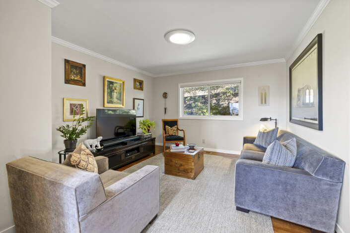 Room with TV and two chairs with art on walls