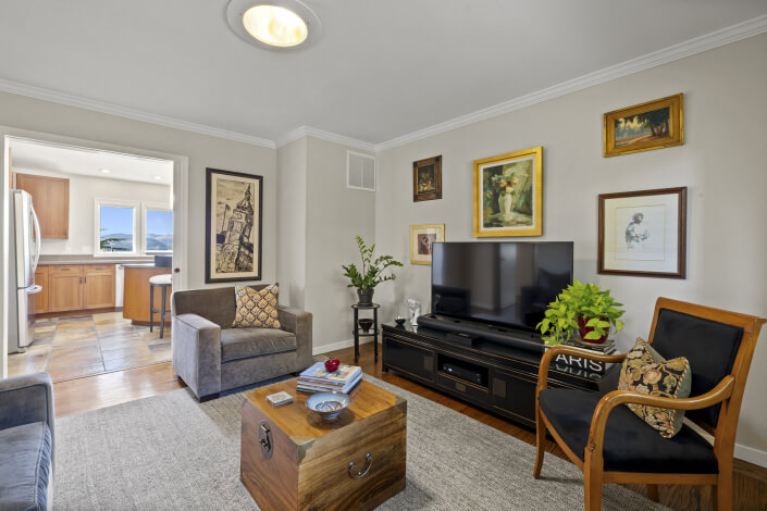 Room with TV and two chairs with art on walls