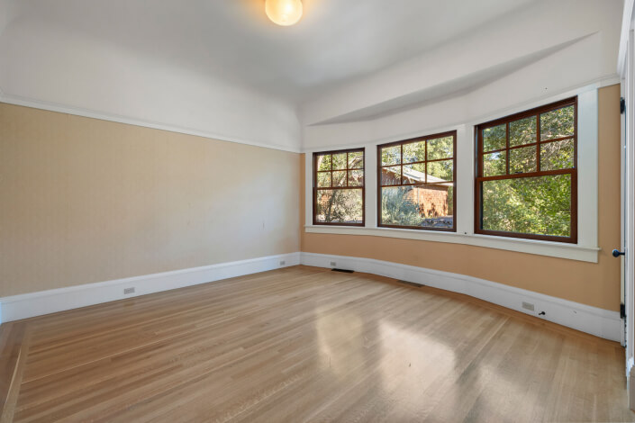 Room with three windows and hardwood floors