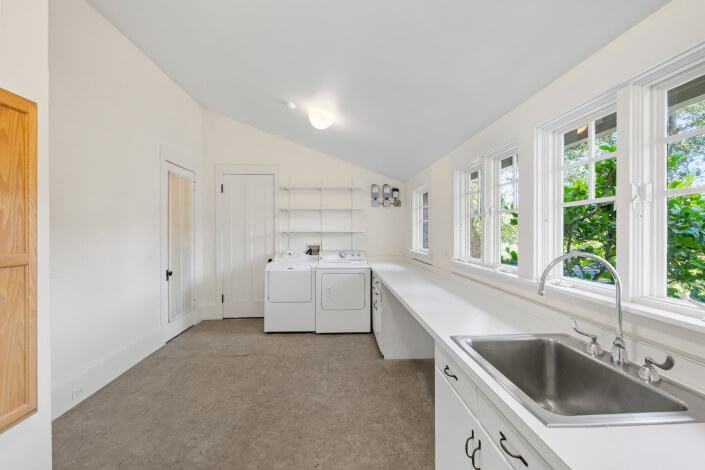 Large white laundry room with windows and sink